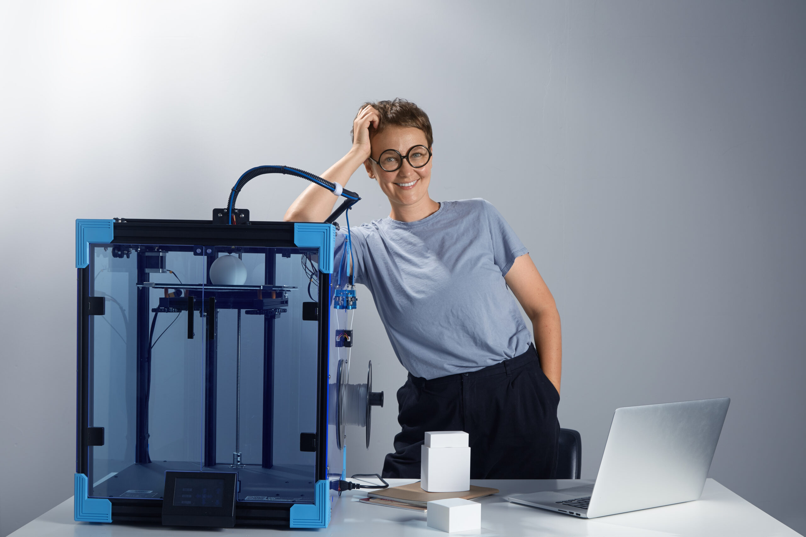 caucasian beautiful lady in the glasses smiling near 3d printing machine in her office new technologies for small businesses concept computer prototypes on the table tech ambient jpg photo scaled